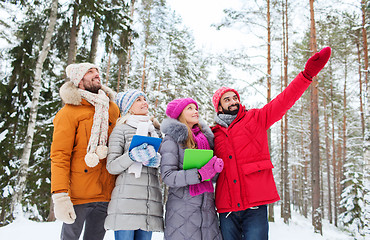 Image showing smiling friends with tablet pc in winter forest