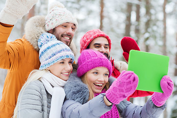 Image showing smiling friends with tablet pc in winter forest