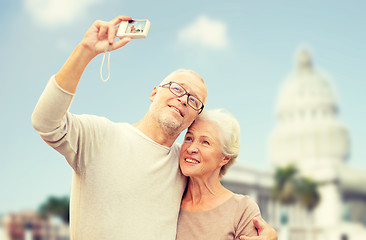 Image showing senior couple with camera over white house