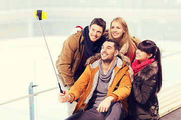 Image showing happy friends with smartphone on skating rink