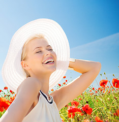 Image showing smiling young woman in straw hat on poppy field