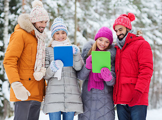 Image showing smiling friends with tablet pc in winter forest