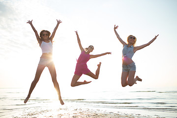 Image showing happy female friends dancing and jumping on beach