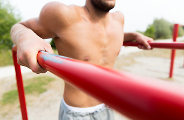 Image showing young man exercising on parallel bars outdoors