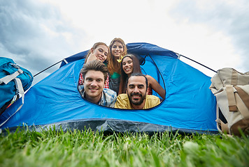 Image showing happy friends with backpacks in tent at camping