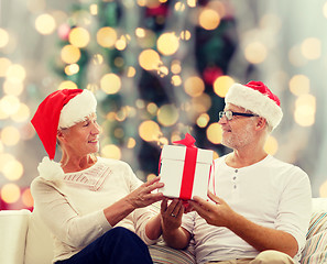 Image showing happy senior couple in santa hats with gift box