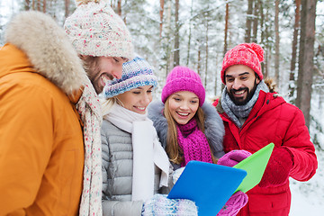 Image showing smiling friends with tablet pc in winter forest