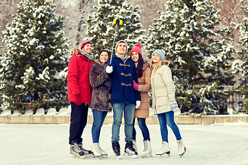 Image showing happy friends with smartphone on ice skating rink