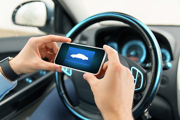 Image showing close up of male hands with car icon on smartphone