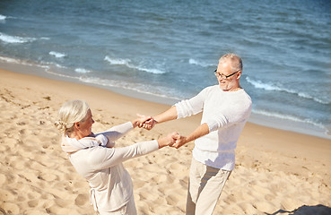 Image showing happy senior couple holding hands on summer beach