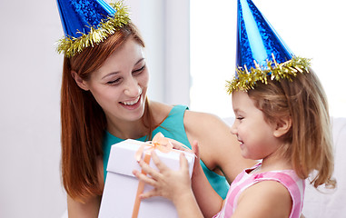 Image showing happy mother and child in party caps with gift box