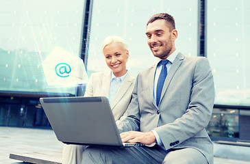 Image showing smiling businesspeople with laptop sending e-mail