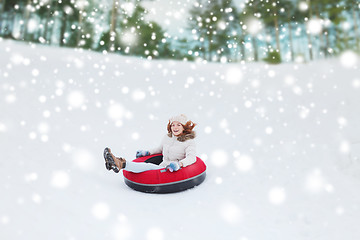 Image showing happy teenage girl sliding down on snow tube