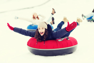 Image showing group of happy friends sliding down on snow tubes