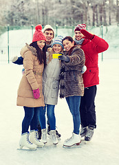 Image showing happy friends with smartphone on ice skating rink