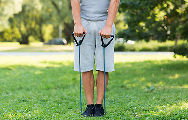 Image showing young man exercising with expander in summer park