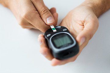 Image showing close up of man checking blood sugar by glucometer