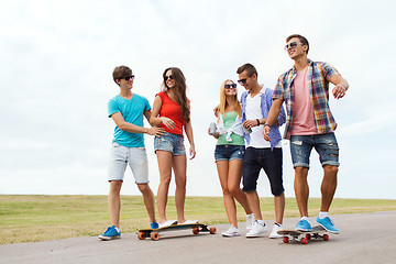 Image showing happy teenage friends with longboards outdoors