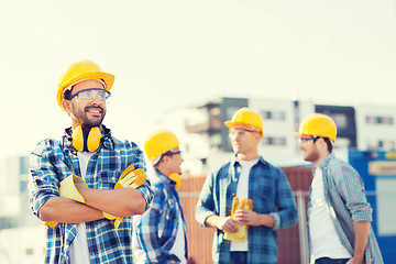 Image showing group of smiling builders in hardhats outdoors