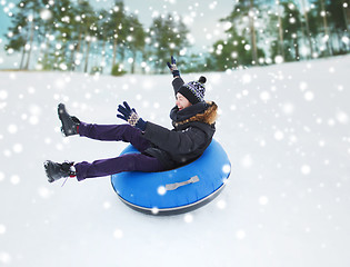 Image showing happy young man sliding down on snow tube