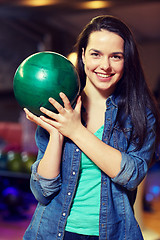 Image showing happy young woman holding ball in bowling club