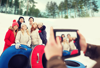 Image showing group of smiling friends with snow tubes