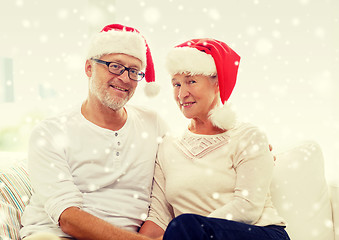 Image showing happy senior couple in santa helper hats at home