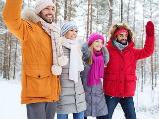 Image showing group of friends waving hands in winter forest