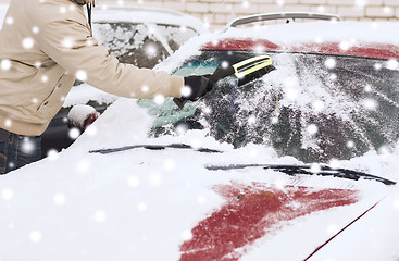 Image showing closeup of man cleaning snow from car