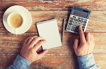 Image showing close up of hands with calculator and notebook