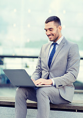 Image showing smiling businessman working with laptop outdoors