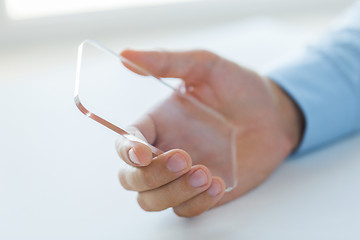 Image showing close up of male hand with transparent smartphone