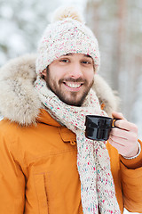 Image showing smiling young man with cup in winter forest