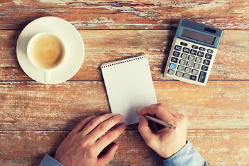 Image showing close up of hands with calculator and notebook