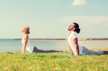 Image showing smiling couple making yoga exercises outdoors