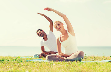 Image showing smiling couple making yoga exercises outdoors