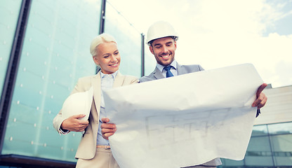 Image showing smiling businessmen with blueprint and helmets