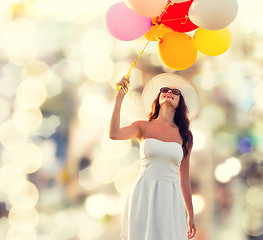 Image showing smiling young woman in sunglasses with balloons