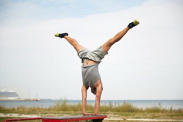 Image showing young man exercising on bench outdoors