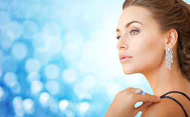 Image showing woman with beautiful diamond earrings over blue