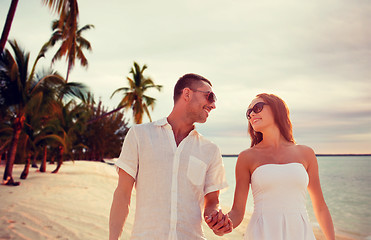 Image showing smiling couple in sunglasses walking on beach