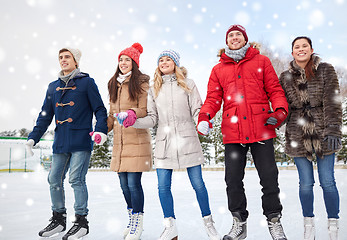 Image showing happy friends ice skating on rink outdoors