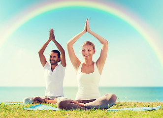 Image showing smiling couple making yoga exercises outdoors