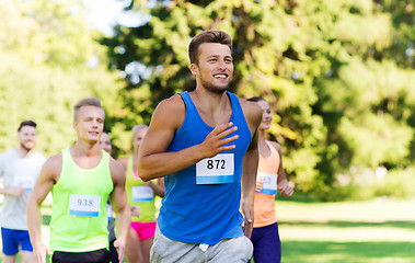 Image showing happy young sportsmen racing wit badge numbers