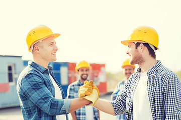 Image showing group of smiling builders in hardhats outdoors