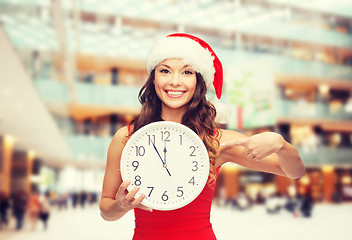 Image showing smiling woman in santa helper hat with clock