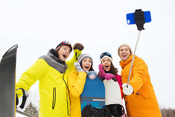 Image showing happy friends with snowboards and smartphone