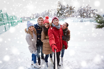 Image showing happy friends with smartphone on ice skating rink