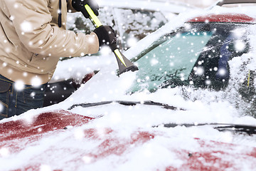 Image showing closeup of man cleaning snow from car