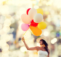 Image showing smiling young woman in sunglasses with balloons